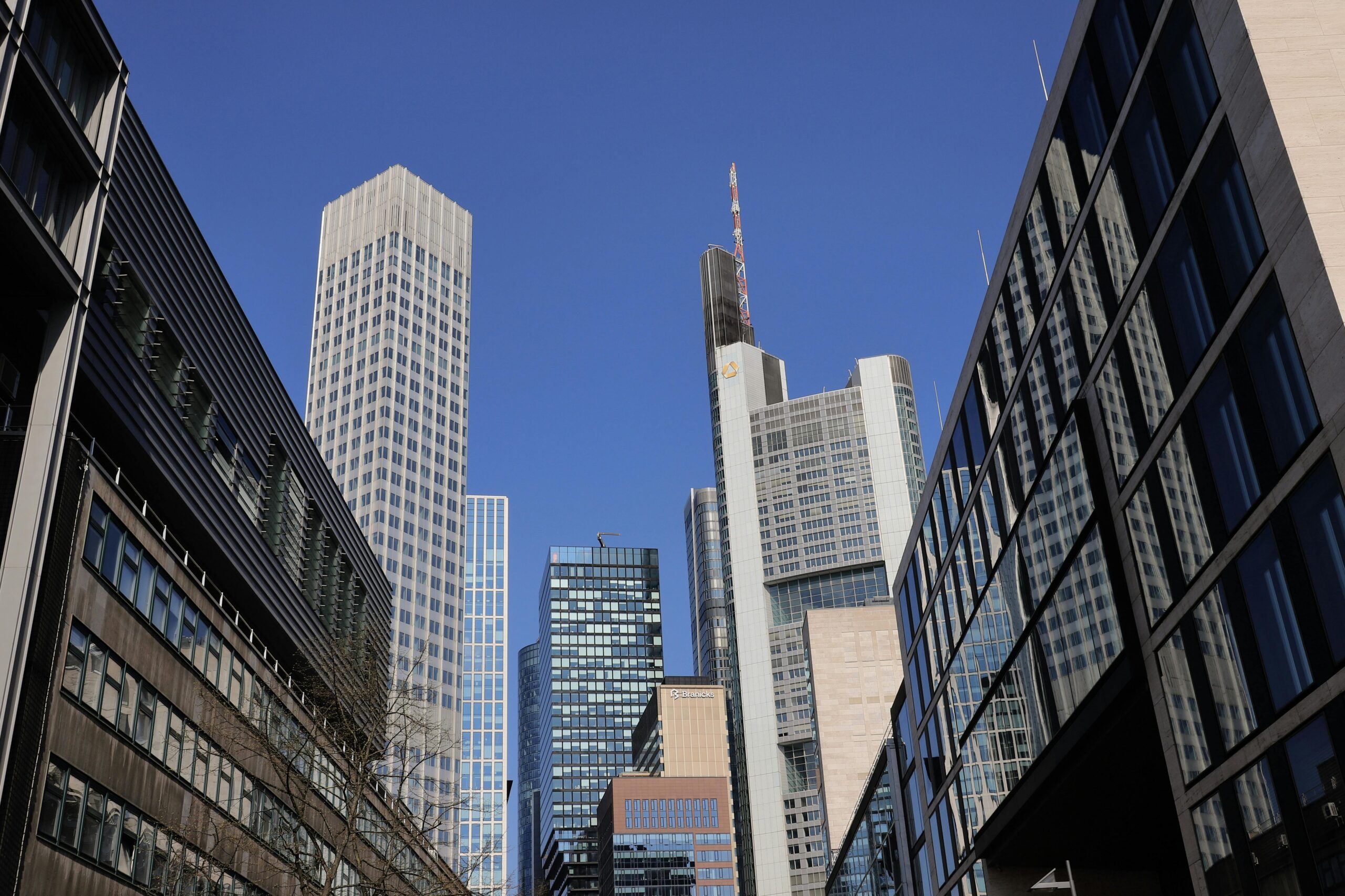 Skyline of skyscrapers in Frankfurt's bustling financial district under a clear blue sky.